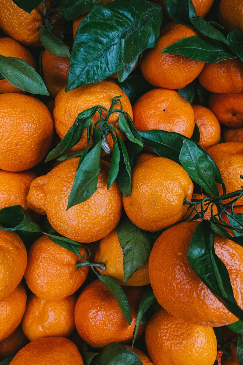 Orangen A pile of oranges with green leaves on them